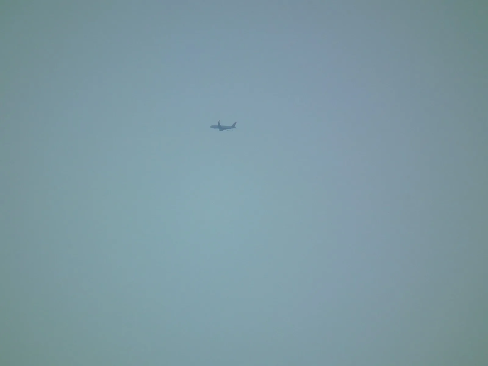 Azami telefotoda, atmosferik pusla yumuşamış yüksek irtifa uçağı